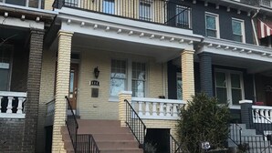 A two-story townhouse with a front porch, a stone wall, and a small garden area. - Charming H St Oasis close to Capitol and museums (Washington)