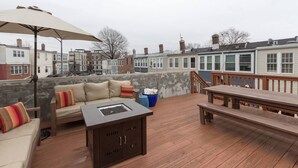 A rooftop deck with a sofa, a fire pit, a table, and an umbrella. - Charming H St Oasis close to Capitol and museums (Washington)
