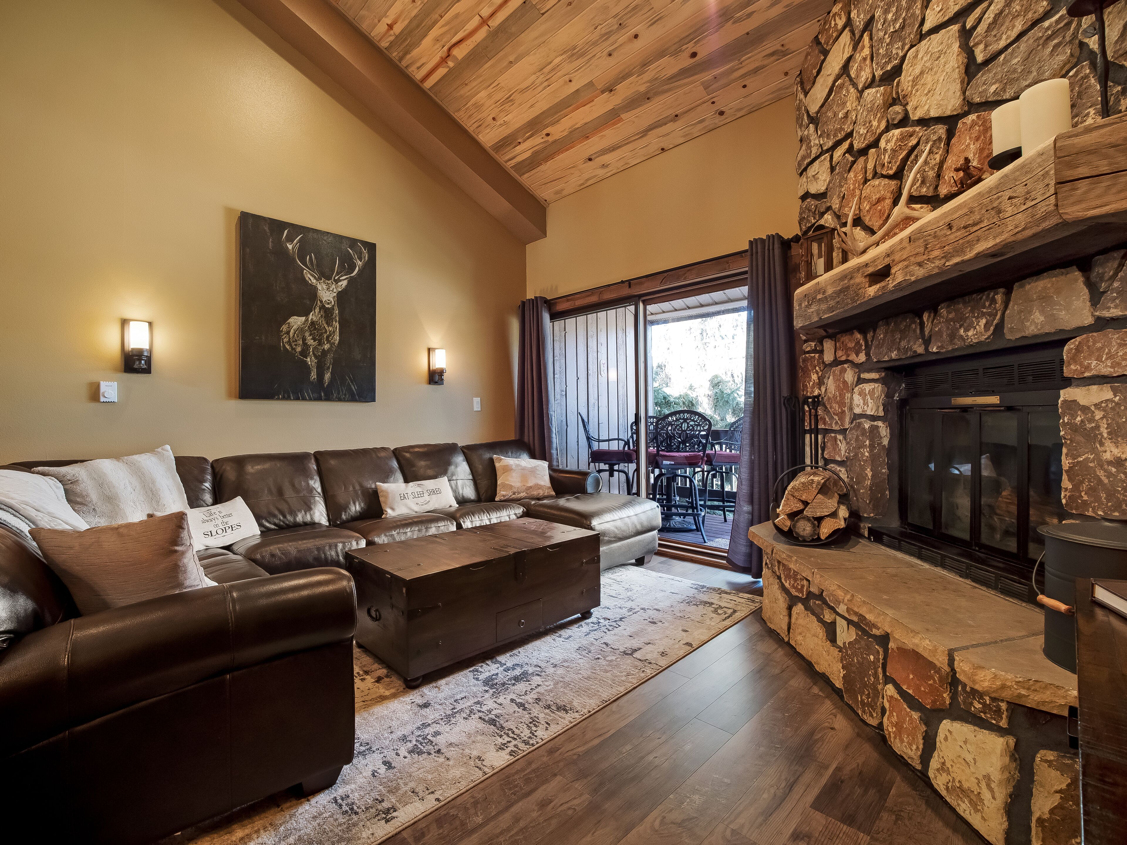 A cozy living room with a stone fireplace, leather sofa, and a large painting.