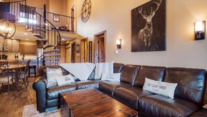 A spacious living room with a leather sofa, a wooden coffee table, and a staircase leading to an upper level.