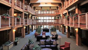 A spacious lobby with multiple levels, wooden balconies, and indoor plants.