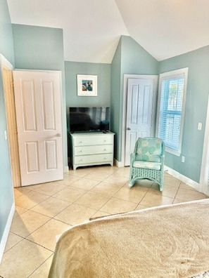 A bedroom with a bed, a dresser, a chair, and a TV.