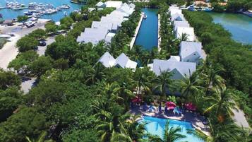 A resort with a central pool, surrounded by palm trees and a marina with boats.