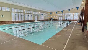 Una piscina interior con carriles delimitados, ventanas y suelo de baldosas.