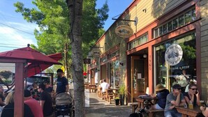 An outdoor seating area with tables and chairs, a stroller, and a dog. - Walkable Sellwood 2BR Apartment (Portland)