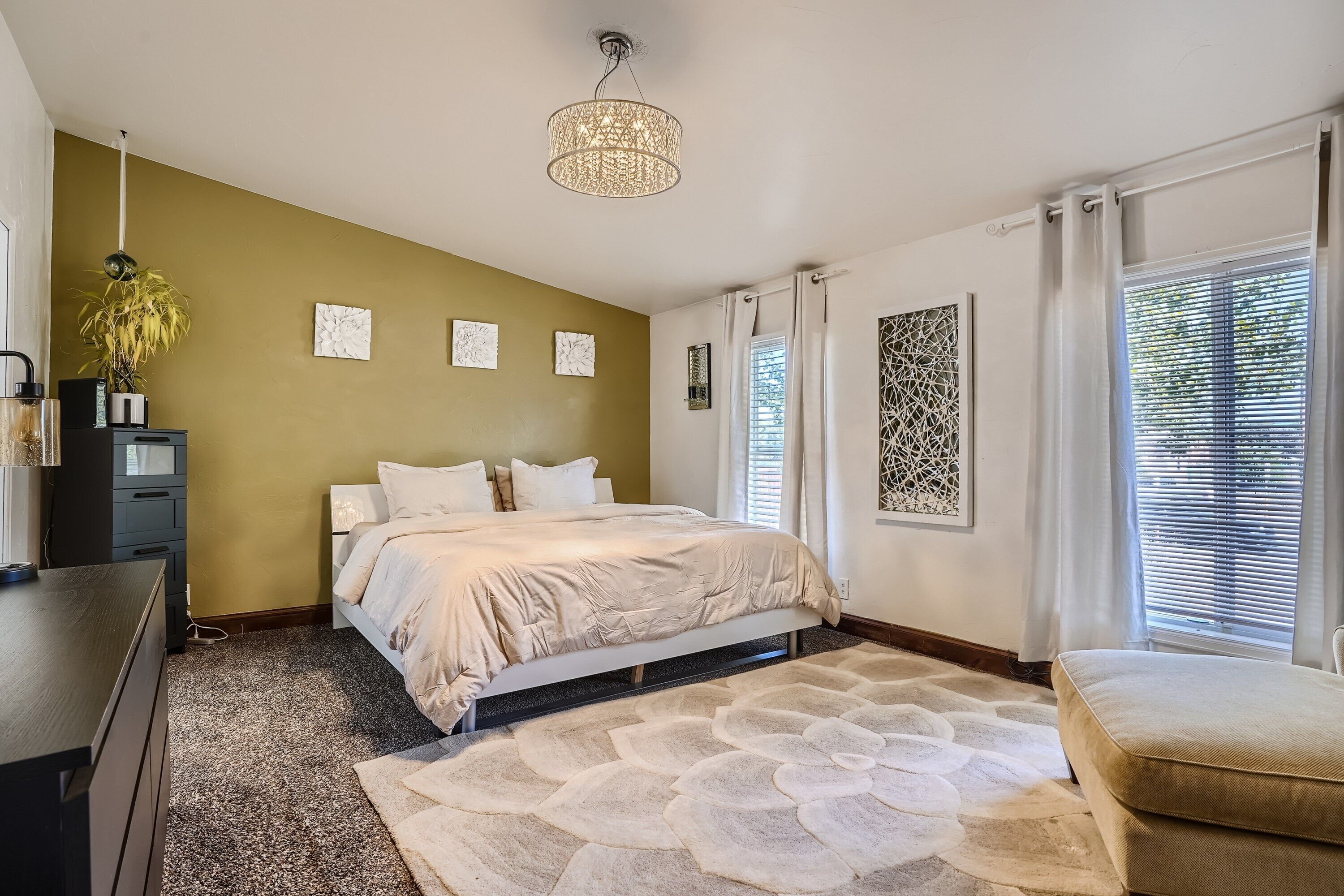 A bedroom with a bed, a desk, a chair, and a decorative rug.