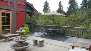 Une terrasse agrémentée d’une fontaine en pierre, de sièges extérieurs et offrant une vue sur les arbres.