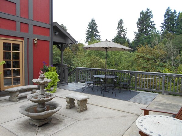 A patio with a stone fountain, outdoor seating, and a view of trees.