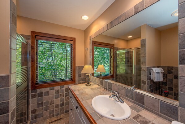 A bathroom with a large mirror, a sink, and a window with blinds. - Architectural Gem w/ Dock & Dock Slip (Swanton)