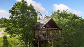 A wooden cabin with a balcony, surrounded by dense greenery and trees. - Canyon View Treehouse- Summer Vacation With A View (Jasper)