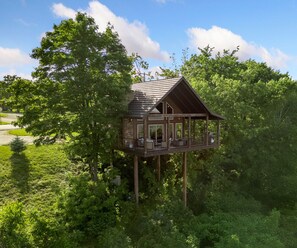 A wooden cabin with a balcony, surrounded by dense greenery and trees. - Canyon View Treehouse- Summer Vacation With A View (Jasper)
