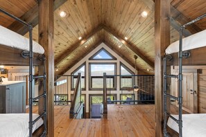 Une chambre spacieuse située sous les combles, avec un plafond en pente, de grandes fenêtres et une vue sur l’extérieur.