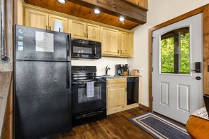 A compact kitchen with a refrigerator, microwave, stove, and dishwasher.
