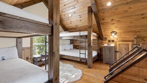 A rustic cabin with bunk beds, a wooden staircase, and a small bathroom. - Canyon View Treehouse- Summer Vacation With A View (Jasper)
