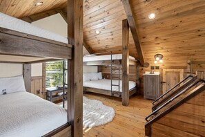 A rustic cabin with bunk beds, a wooden staircase, and a small bathroom. - Canyon View Treehouse- Summer Vacation With A View (Jasper)