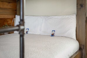 Un letto con biancheria bianca e due barrette di cioccolato sopra.