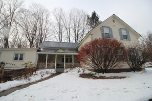 A two-story house with a porch and a covered front entrance. - Ski, Snowboard, Hike, or just Relax at our Spacious Home for Family and Friends! (Saxtons River)