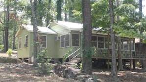 Een chalet met twee verdiepingen, een overdekte veranda en een trap naar een hoger niveau.