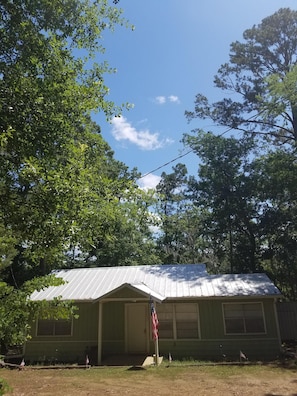 Set amidst a wooded area, this charming home features a front porch and a classic gabled roof.