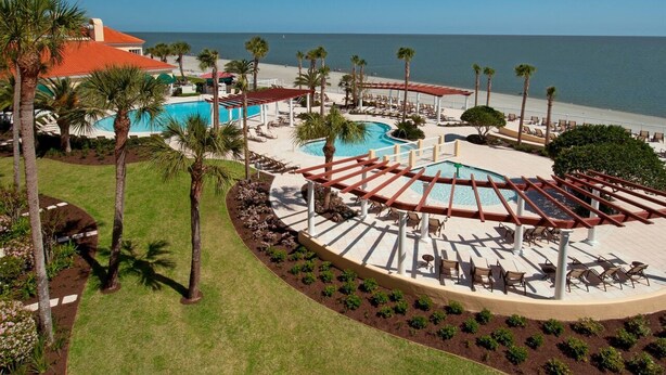 Un complexe hôtelier doté d’une grande piscine, de palmiers et offrant une vue sur la plage.
