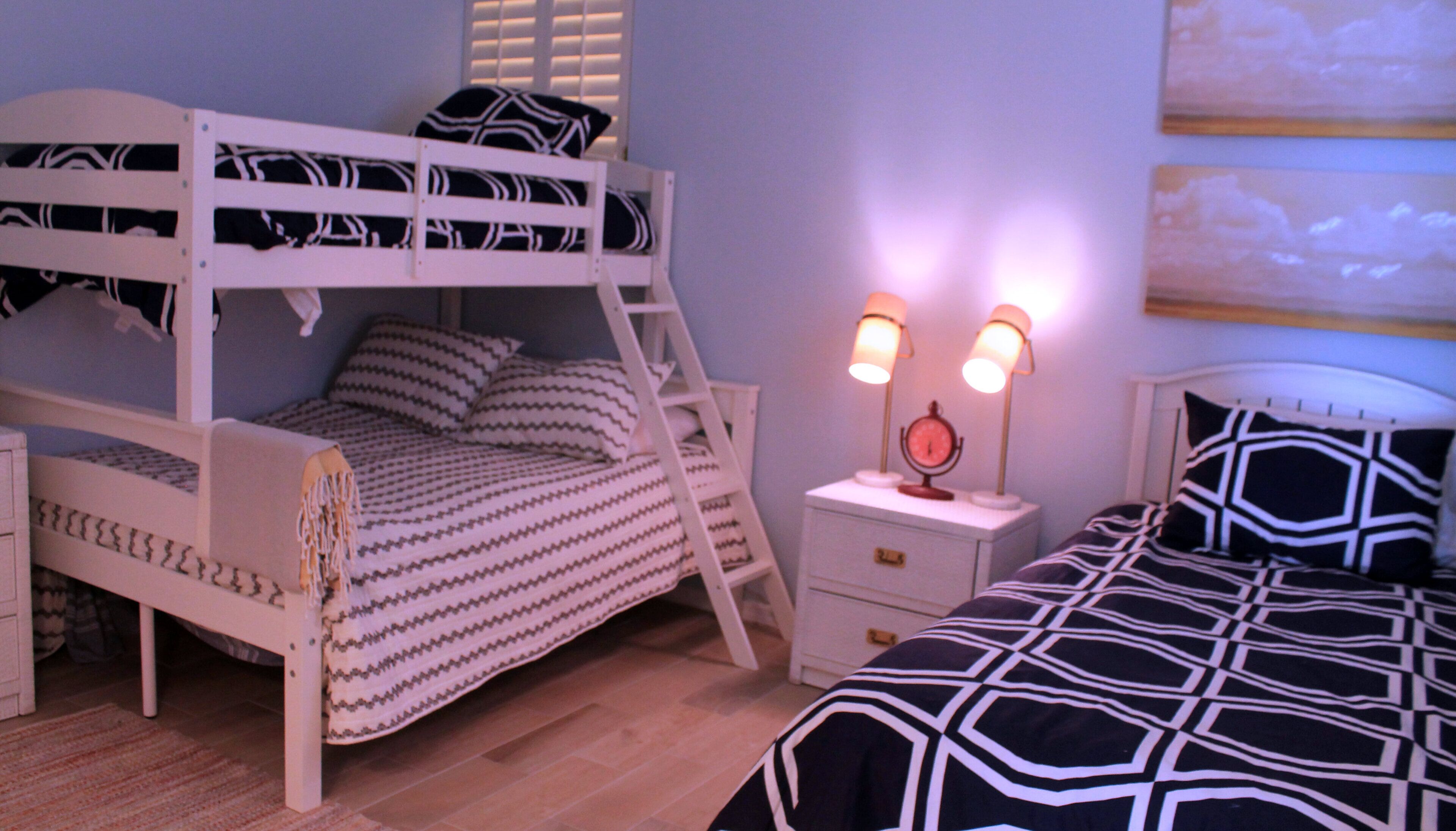 A bunk bed with a ladder, a bedside table with a clock, and a lamp.