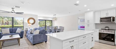 A modern kitchen with white cabinetry, a central island, and stainless steel appliances.