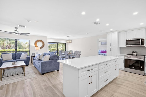 A modern kitchen with white cabinetry, a central island, and stainless steel appliances.