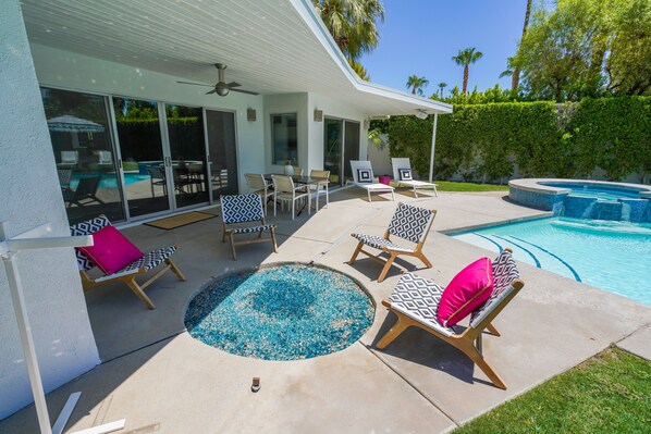 A pool area with lounge chairs and a hot tub.