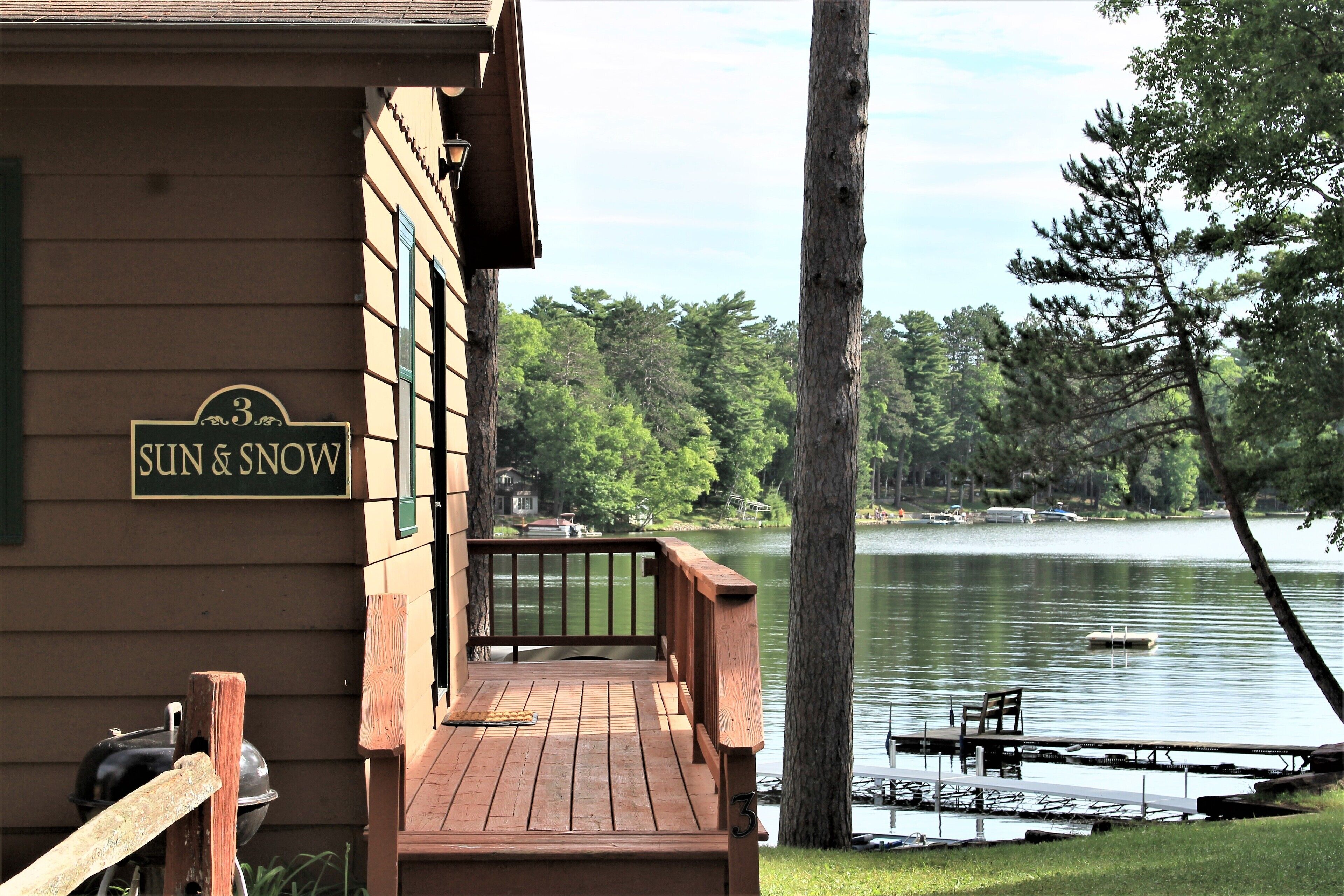 A wooden deck with a grill and a sign reading "Sun & Snow".