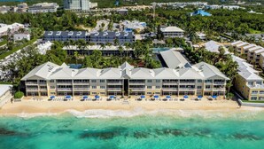 A beachfront hotel with multiple balconies, a sandy beach, and clear turquoise waters.