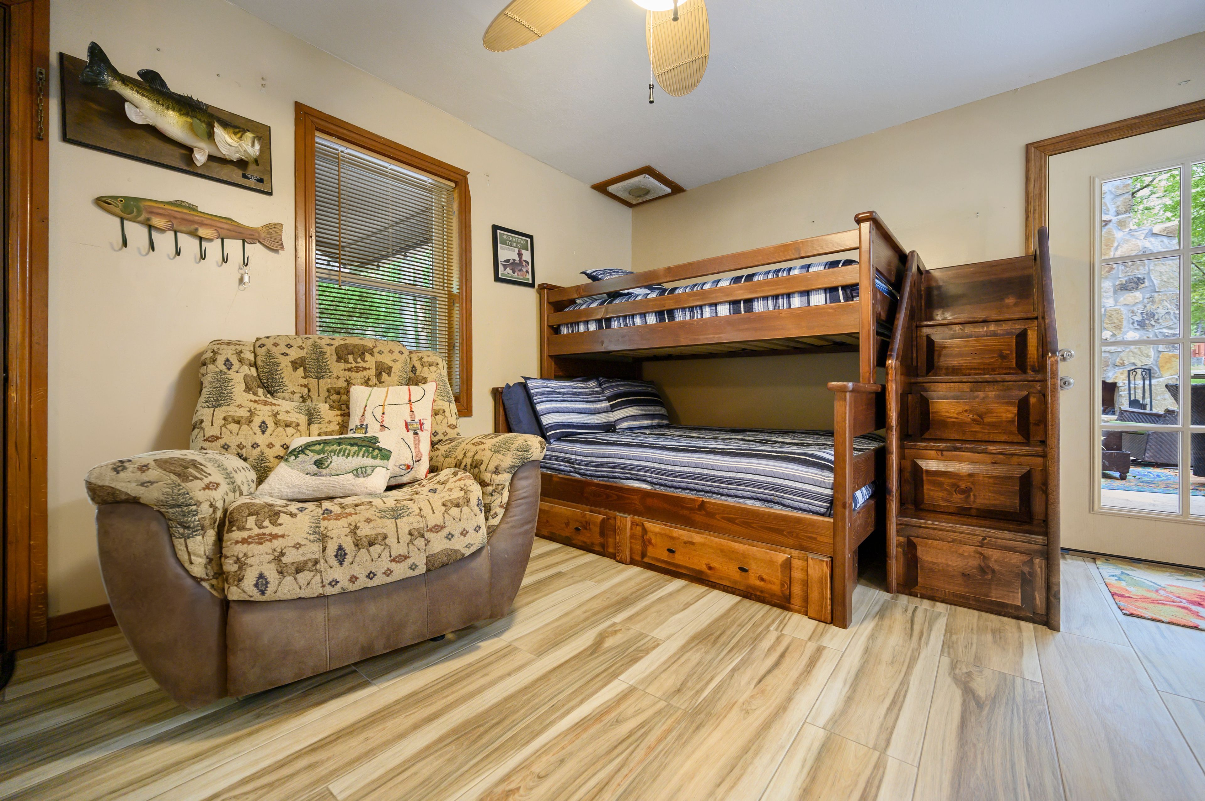 A cozy room with a bunk bed, a patterned armchair, and a fish wall art piece.