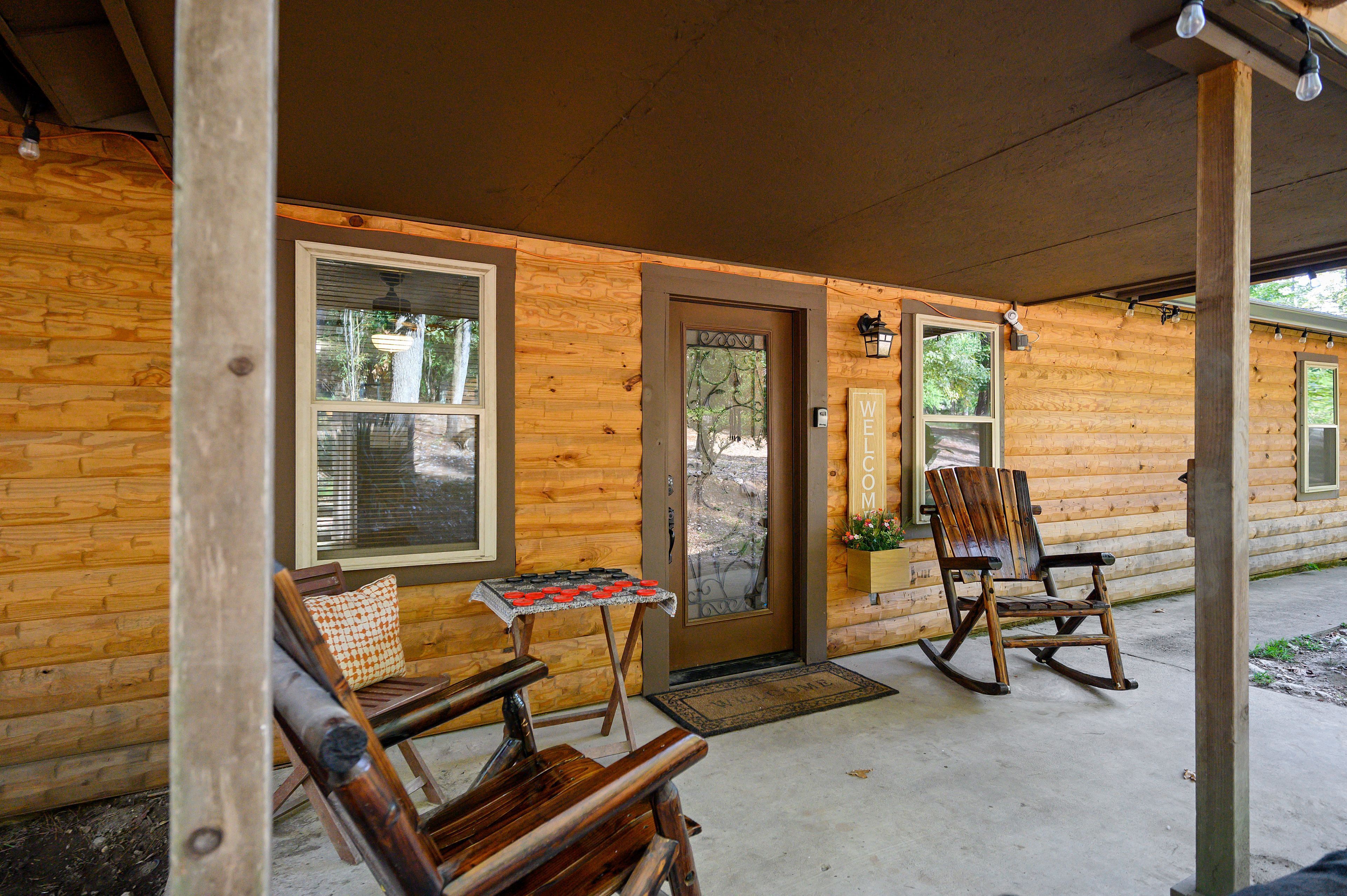 A wooden cabin with a porch, a rocking chair, and a table with a checkered cushion.