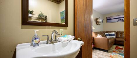 A bathroom with a white sink, a mirror, and a bottle of hand soap.