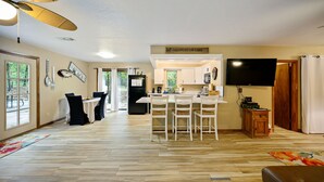 A spacious living area with a dining table, chairs, a kitchen area, and a television. - Boomer Bed & Bass; 2 bedroom, 2 bathroom family cabin. (Broken Bow)