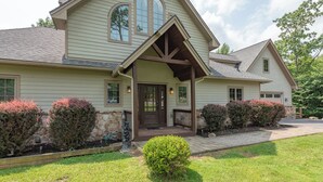 A two-story house with a front porch, stone foundation, and a well-maintained lawn. - Luxury Mountain Escape w/ Community Perks (McHenry)