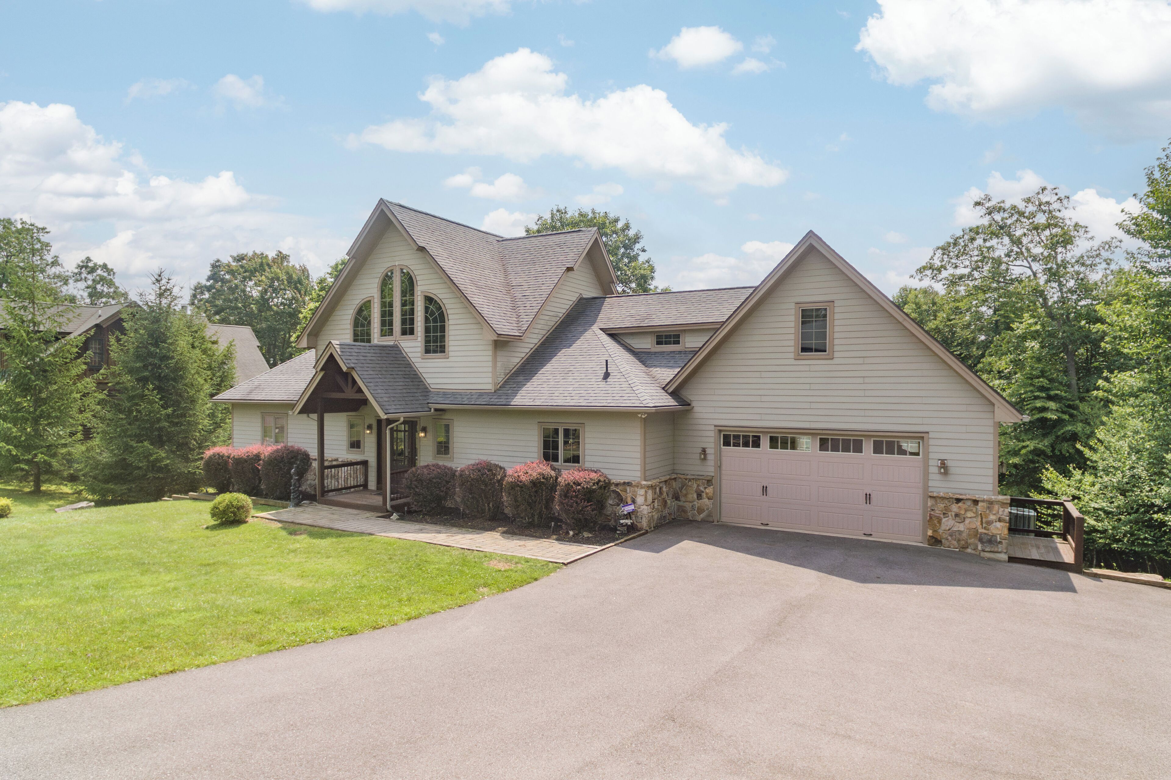 A two-story house with a garage, a covered porch, and a well-maintained lawn.