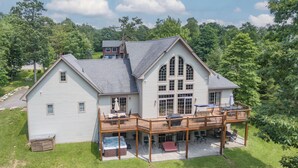 A large two-story house with a covered patio, a hot tub, and a deck. - Luxury Mountain Escape w/ Community Perks (McHenry)