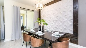 A modern dining area with a dark wooden table, four copper chairs, and a geometric-patterned wall. - Private Pool + Themed kids rooms! * Near Disney! (Davenport)