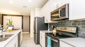 A modern kitchen with stainless steel appliances, white cabinetry, and a tiled backsplash. - Private Pool + Themed kids rooms! * Near Disney! (Davenport)
