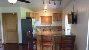 Una cocina con armarios de madera, encimera de granito y horno empotrado. Hay tres sillas de madera alrededor de la isla.
