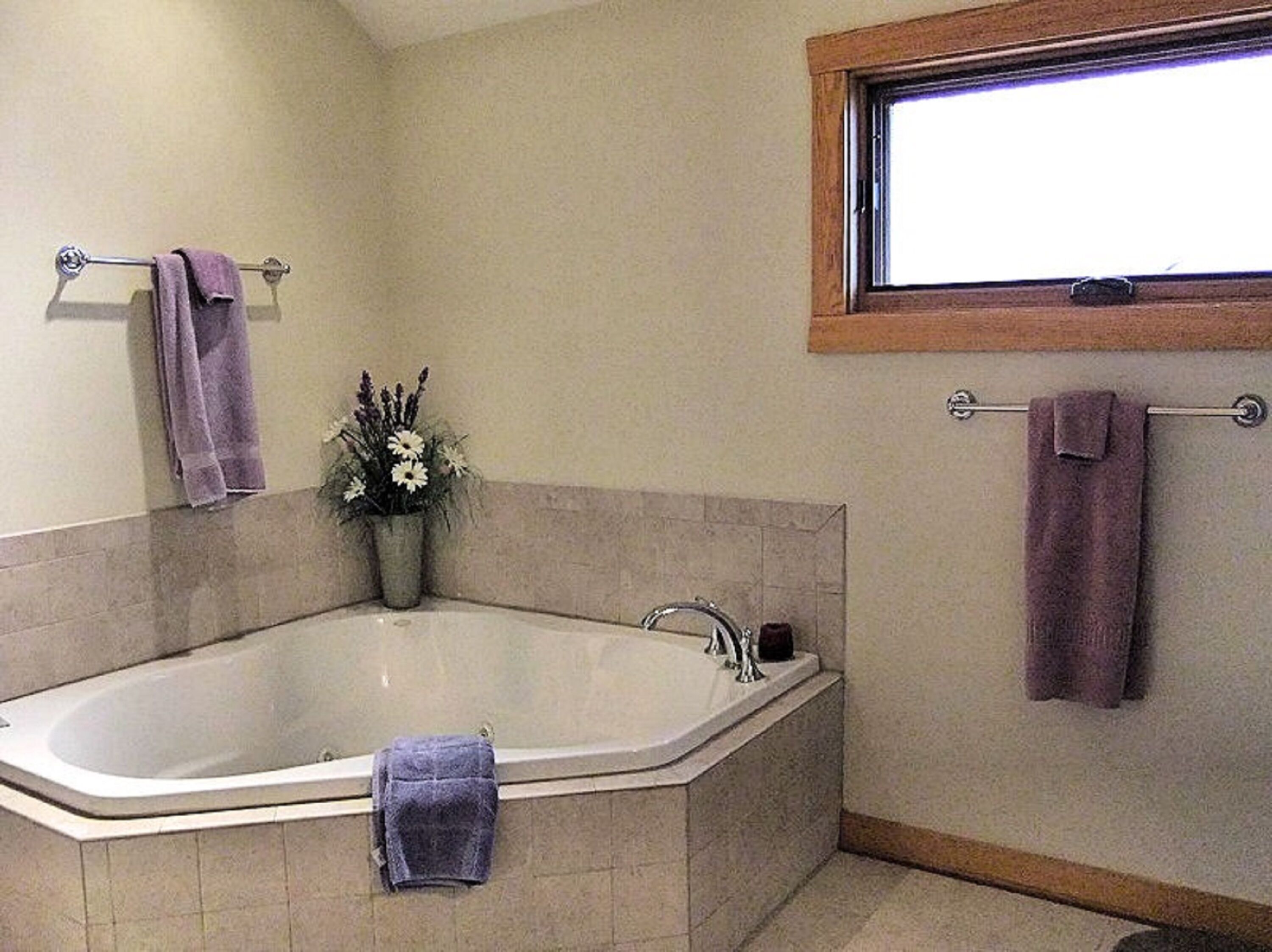 A bathroom with a freestanding bathtub, a window above the tub, and two towels hanging on towel bars.