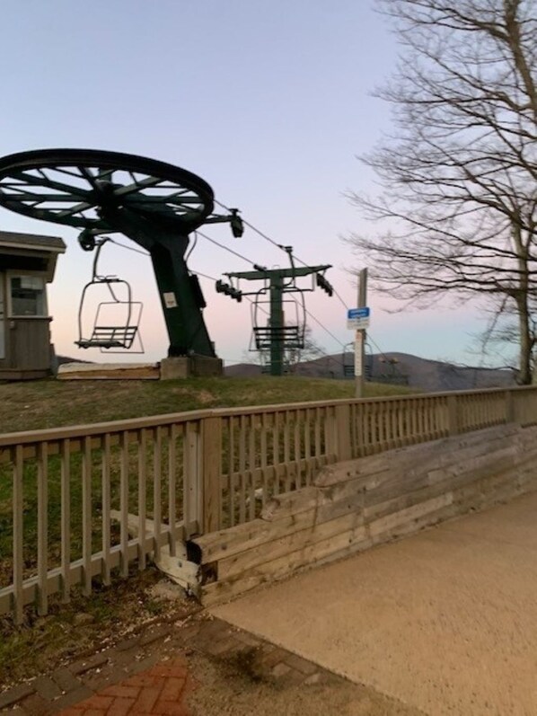 A ski lift with chairs, a wooden fence, and a stone wall.