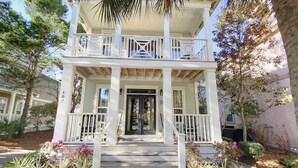 A two-story building with a balcony, a front door, and steps leading up to the entrance. - Beautiful Home at the Front of Seacrest- 3 Bikes (Panama City Beach)