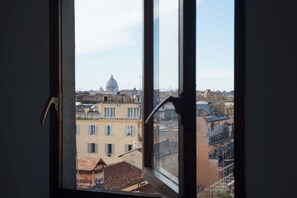A view through a window of a cityscape with a prominent dome structure in the distance. - Angelo Brunetti 24 - FromHometoRome (Roma)