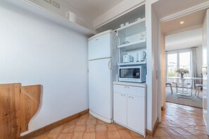 A compact kitchen with white cabinets, a built-in microwave, and a refrigerator. - Angelo Brunetti 24 - FromHometoRome (Roma)