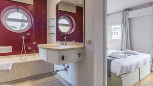 Een moderne badkamer met een dubbele wastafel, een grote spiegel en een bad.