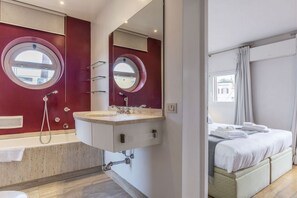 A modern bathroom with a double sink, a large mirror, and a bathtub.