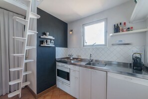 A modern kitchen with white cabinets, a stainless steel countertop, a built-in oven, and a window above the sink. - Angelo Brunetti 24 - FromHometoRome (Roma)