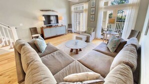 A living room with a large beige sectional sofa, a round coffee table, and a television.