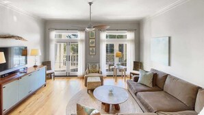 A spacious living room with a sofa, a coffee table, and a television on a wooden cabinet.